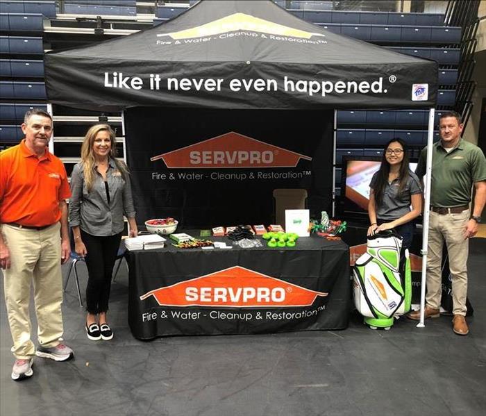 4 people around a SERVPRO tent